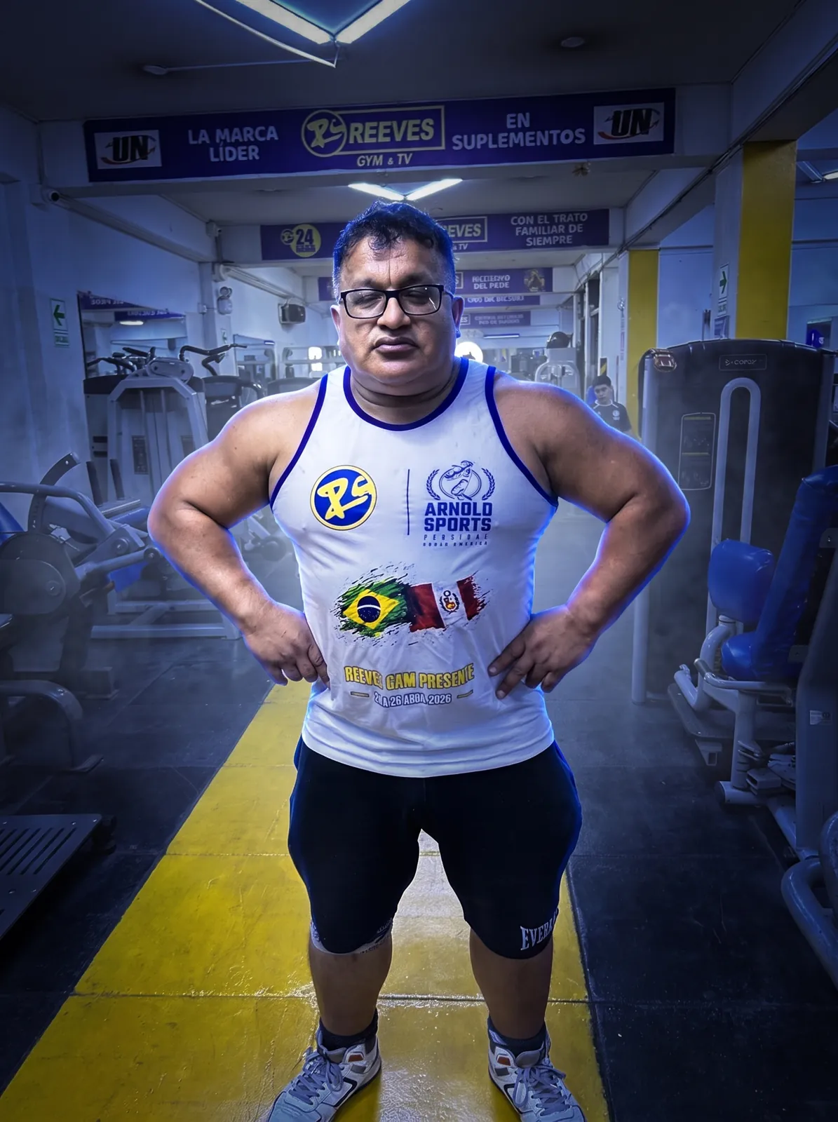 Marco Antonio Reeves de pie en la sala de máquinas de Reeves Gym, con las manos en la cintura