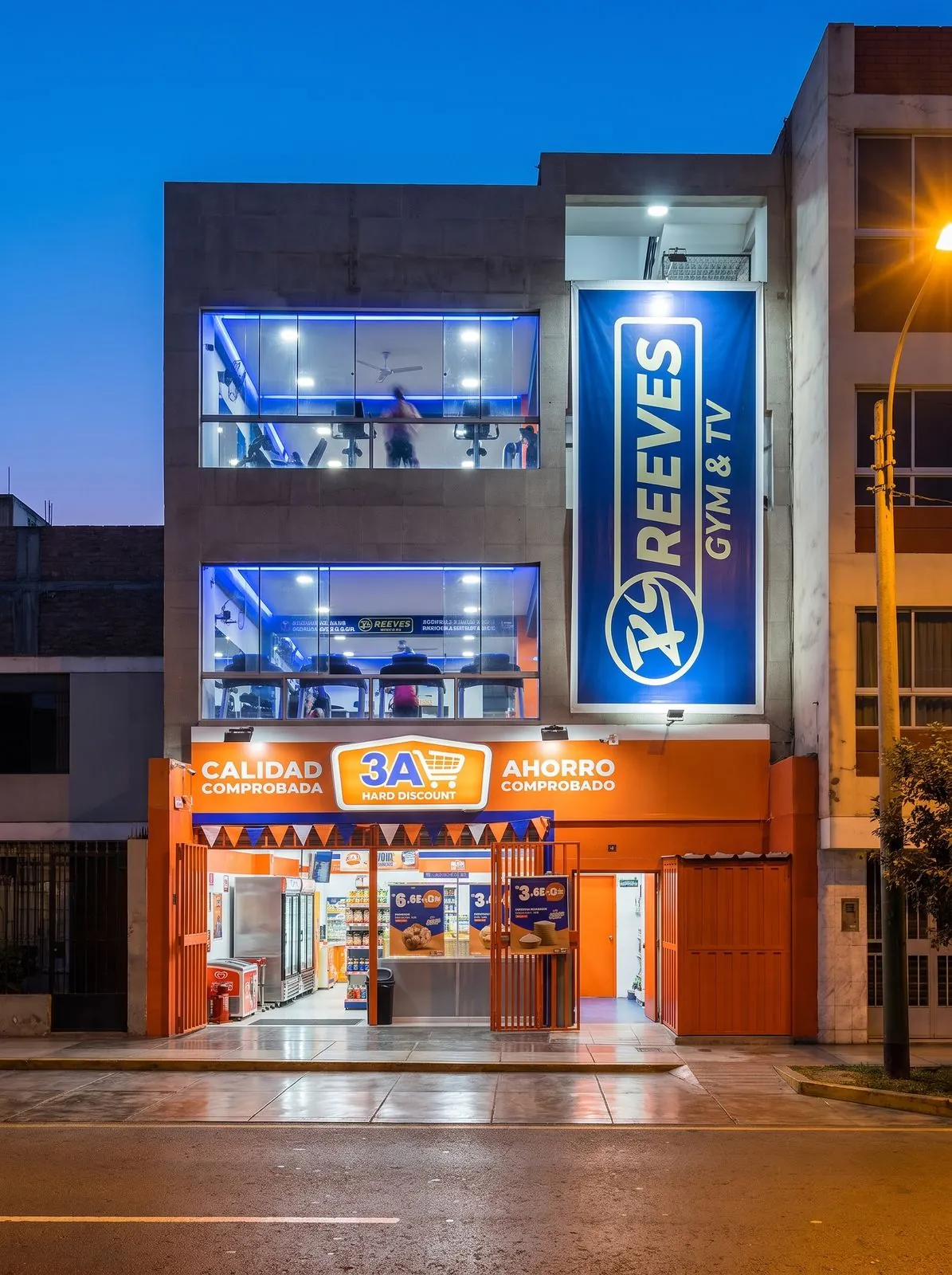 Fachada de Reeves Gym de noche, con su letrero azul iluminado sobre la tienda
